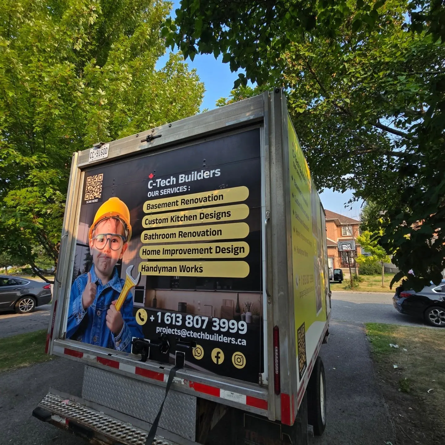 Printed rear door panel on a cube van listing renovation services with contact details and a QR code