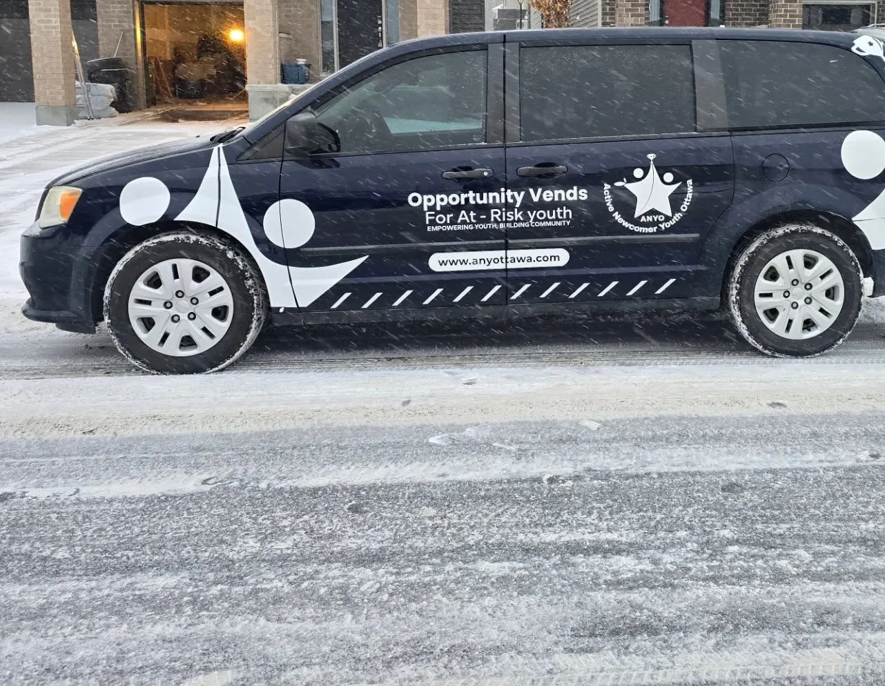 Navy minivan with white shapes, ANYO logo and programme lettering along the side
