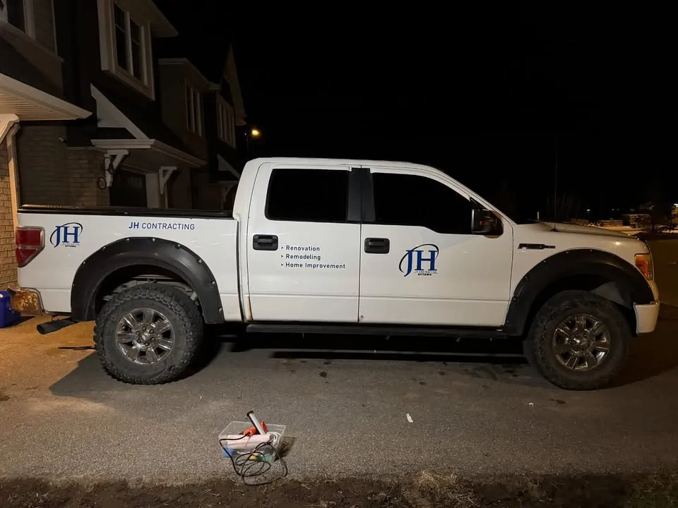 White crew cab pickup with JH Contracting logo on the door and bed side, plus a services list in cut vinyl